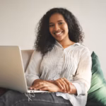 portrait-cheerful-young-african-woman-jeans-shirt-smiling-broadly-while-surfing-internet-generic-portable-computer-enjoying-high-speed-wireless-connection-living-room_343059-1548